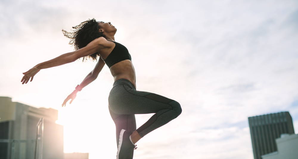 Young woman exercising outside with arms wide open