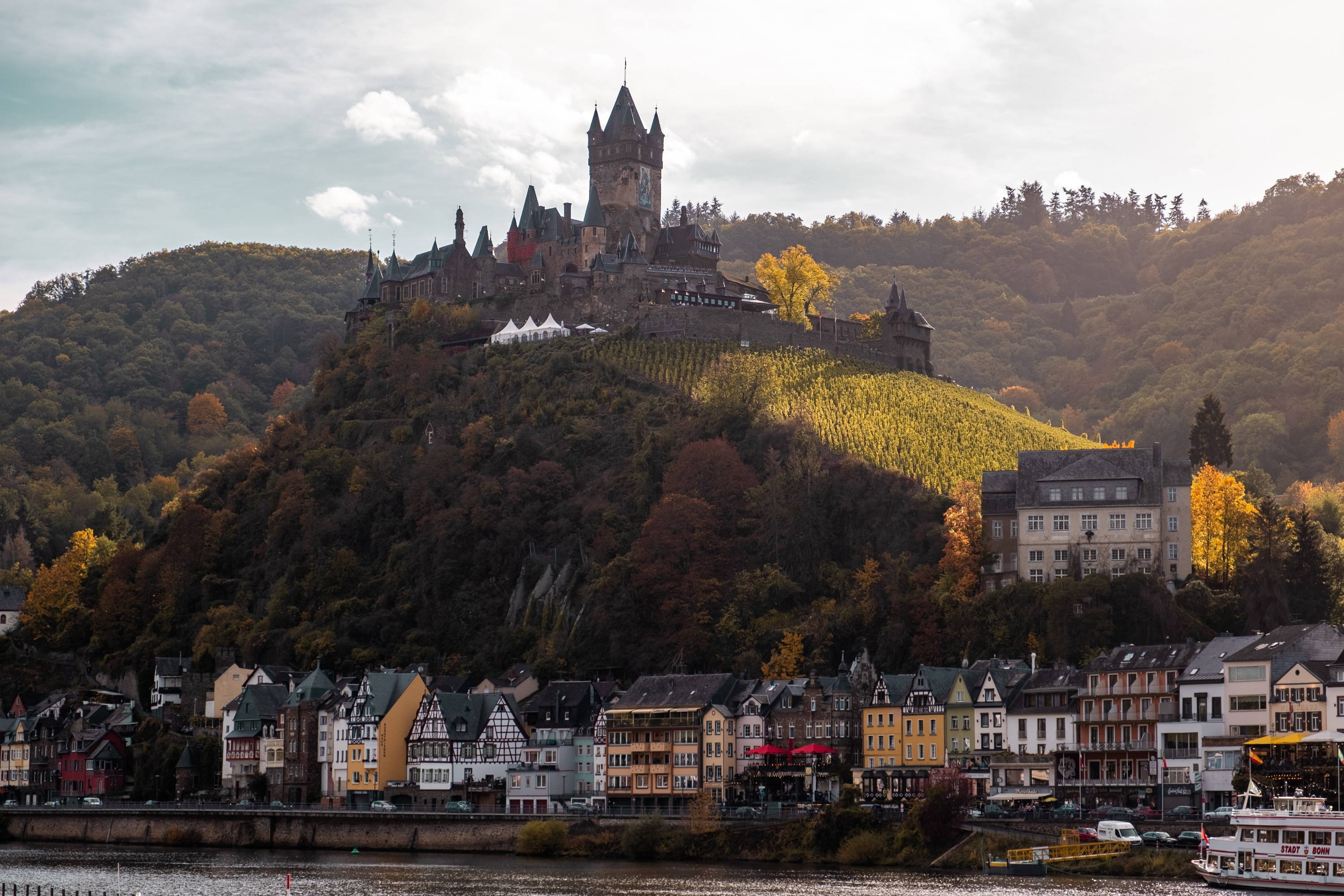 German wine town along the river, with castle and vineyard on the hill. 