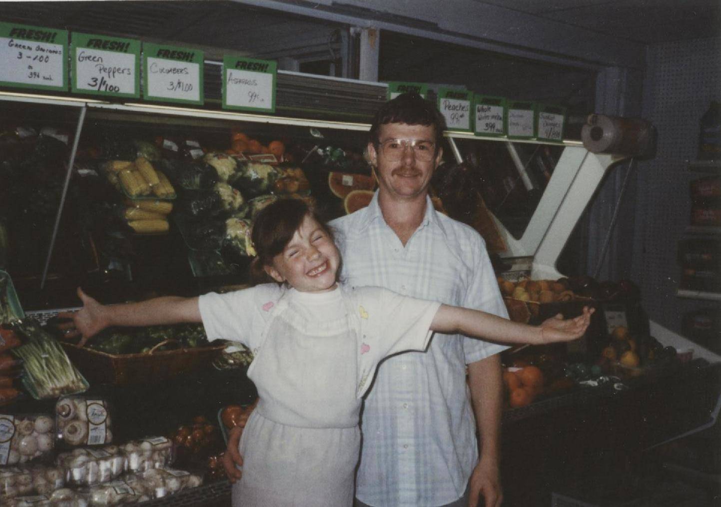 Photo of me, Christina Appleton, and my father in front of a fresh produce and vegetable case in Appleton's Market. I found my love of fresh high quality ingredients and love of food 