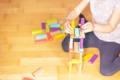Close up on a girl stacking colorful wooden blocks and making a tower.