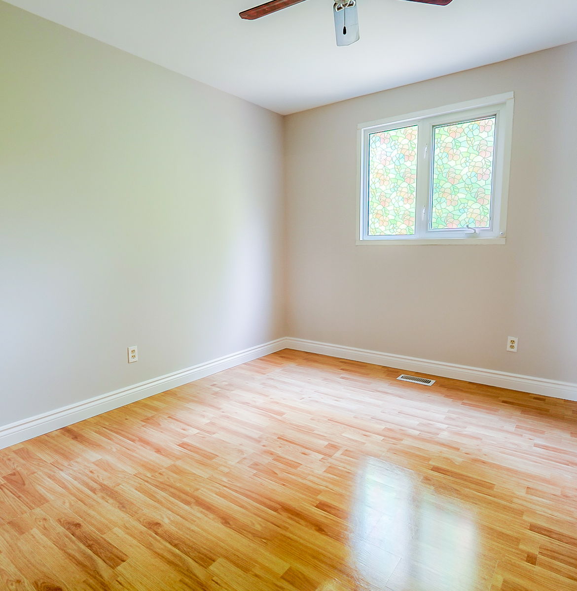 empty room featuring a ceiling fan, wood-type flooring, and natural light