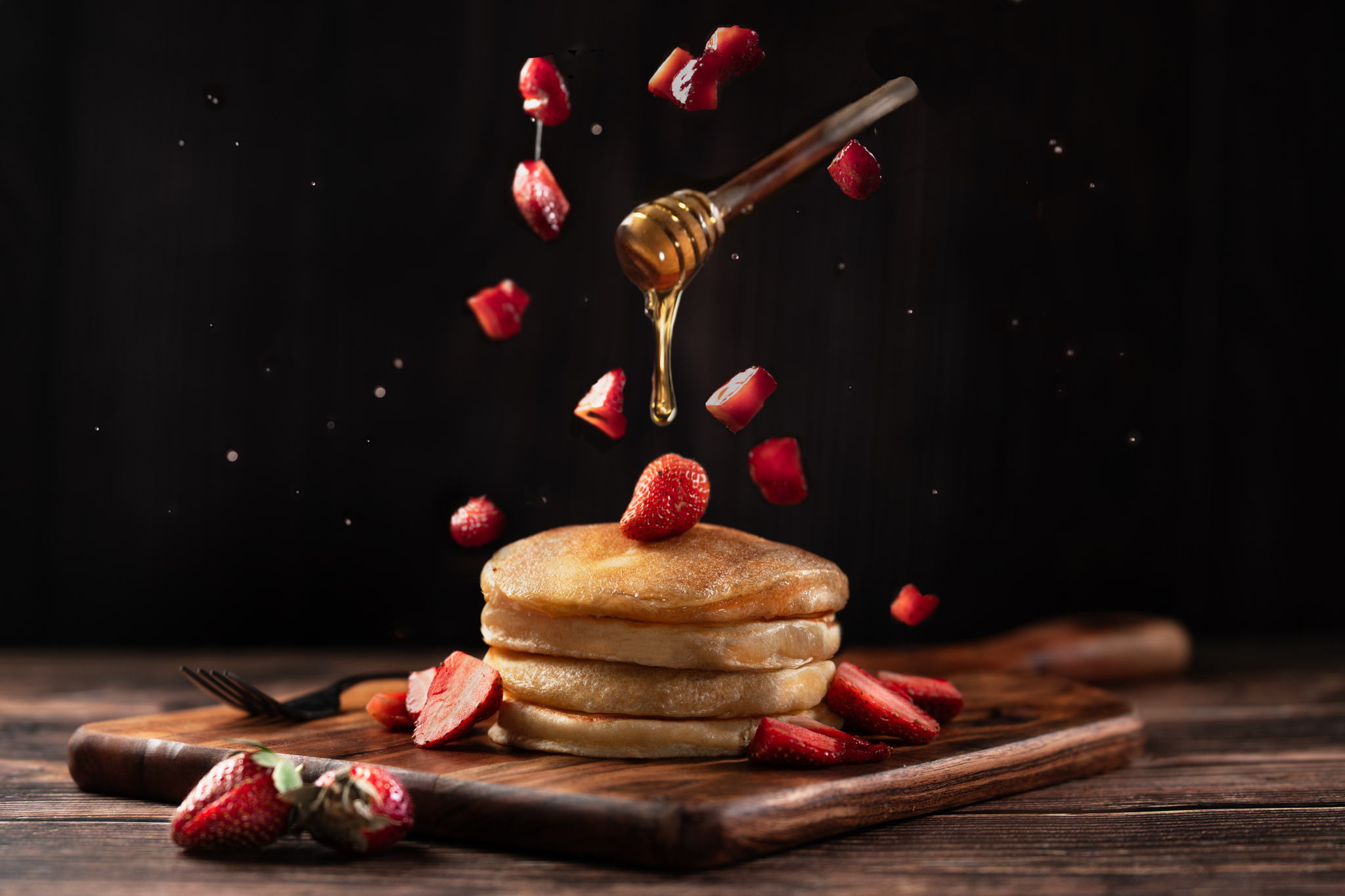 Food Photography of Stack of fluffy pancakes with fresh strawberries and honey drizzle on a wooden board