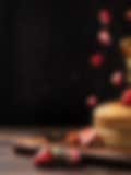 Food Photography of Stack of fluffy pancakes with fresh strawberries and honey drizzle on a wooden board