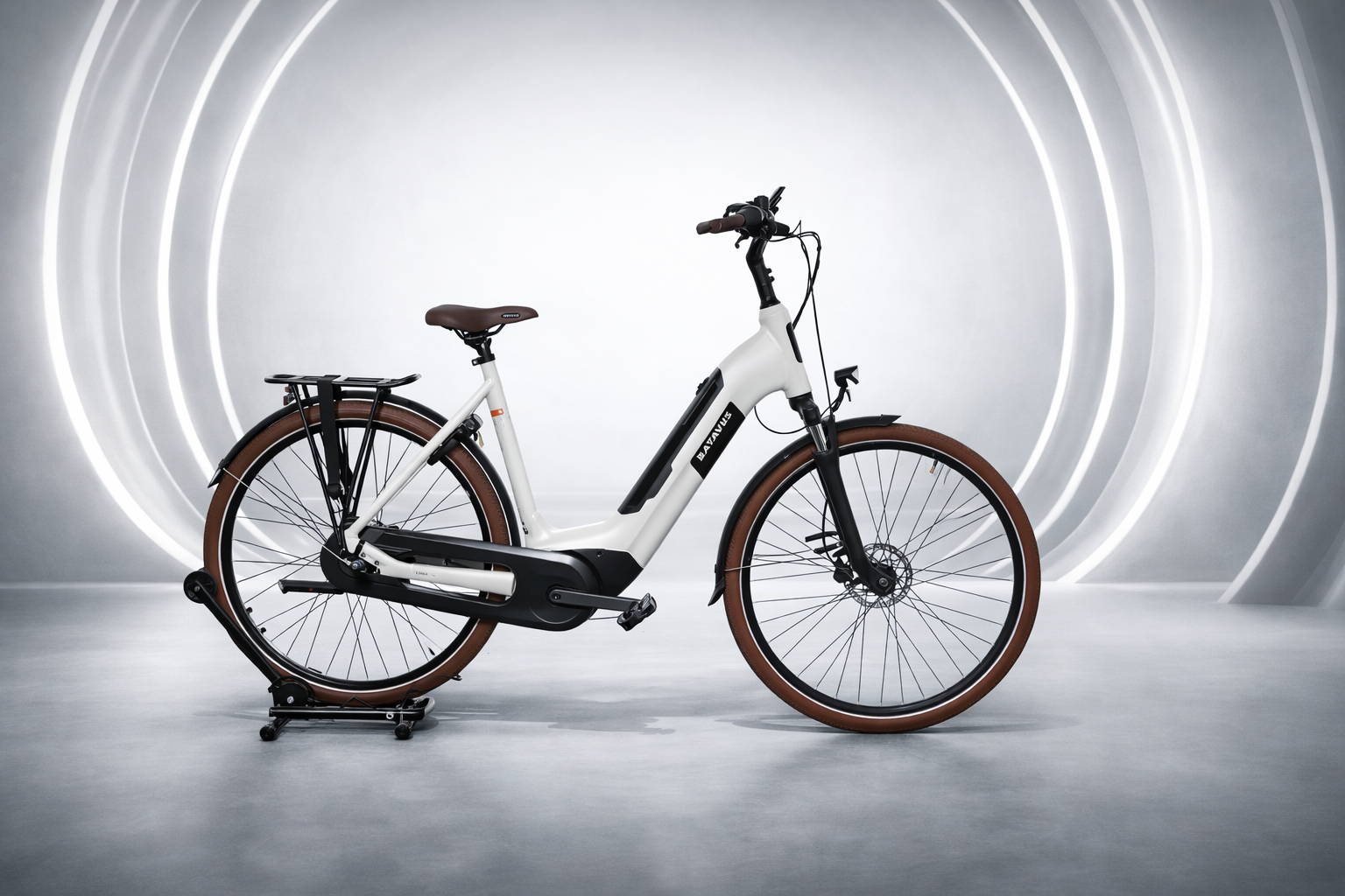 Batavus Altura E-go Power Pro in lichtgrijze uitvoering met geïntegreerde accu, middenmotor, bruine banden en stevige bagagedrager, gefotografeerd in neutrale studio-opstelling voor review.