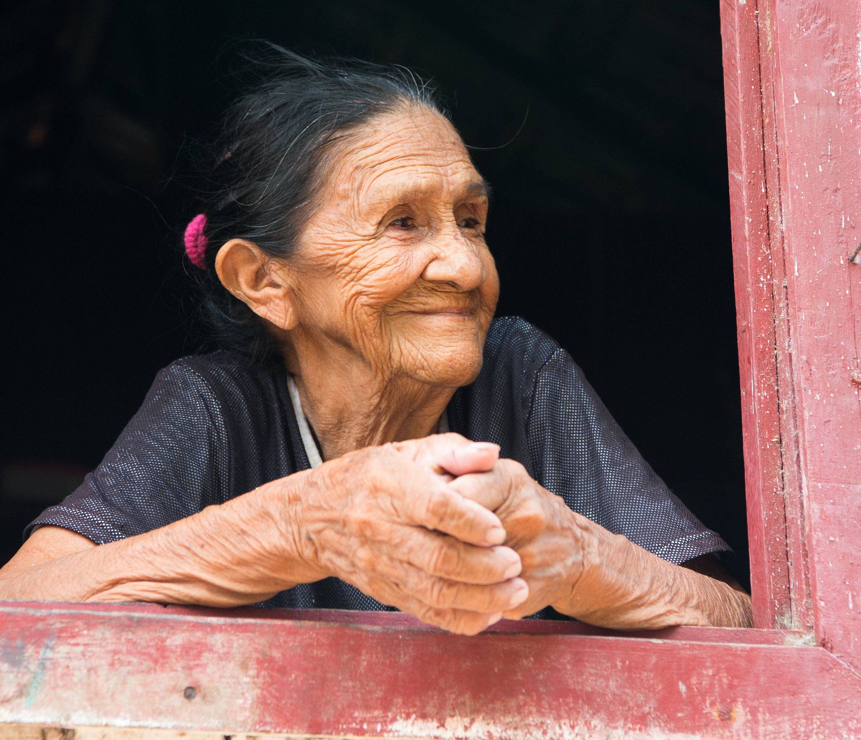 Elderly Brazilian woman gazing out of window