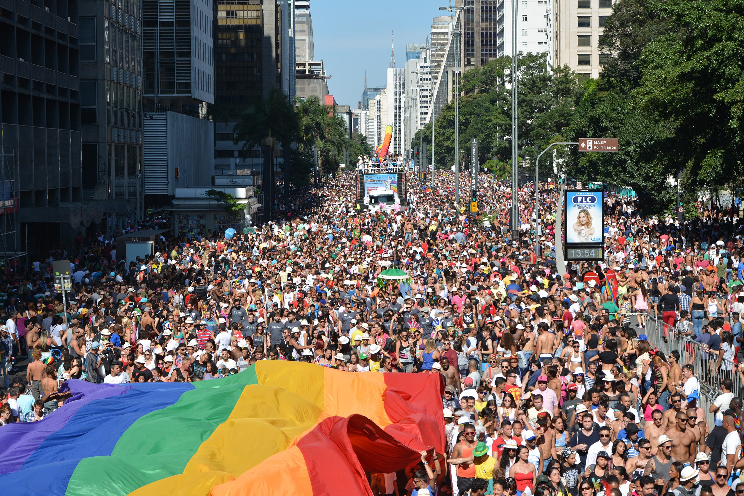 An incredible scene of thousands of people marching with a very large rainbow flag among them.