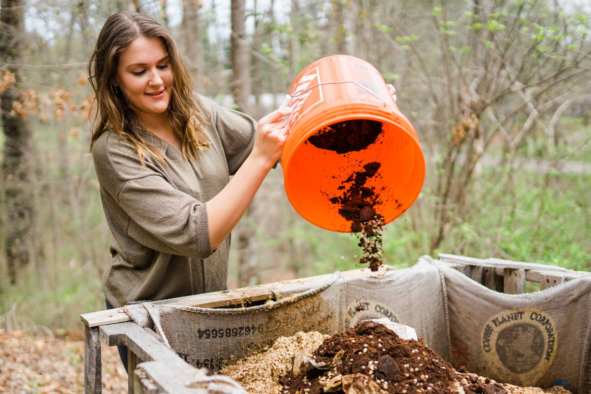Woman pouring used coffee grounds into compost