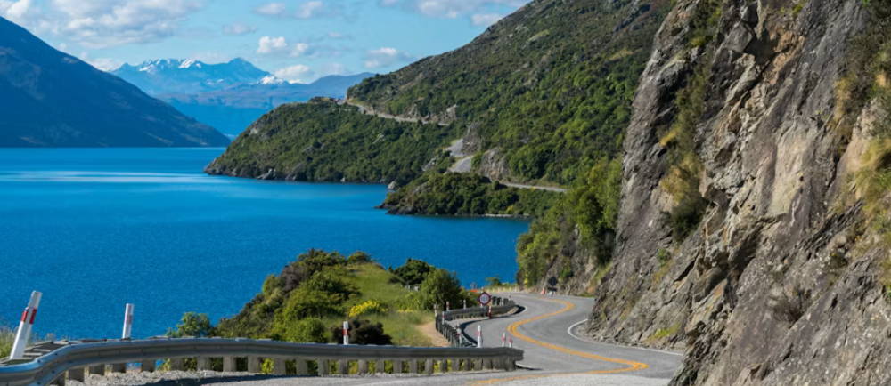a winding road next to water and mountains