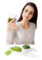 young lady looking at a glass of wheat grass juice, with wheat grass powder and tablets in front of her