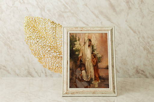 LDS art small art of Christ comforting two people.  It is set up next to a complimenting fall leaf accent. 