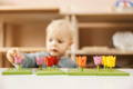 Little boy playing with wooden  multicolor Montessori flower stacking toy. 