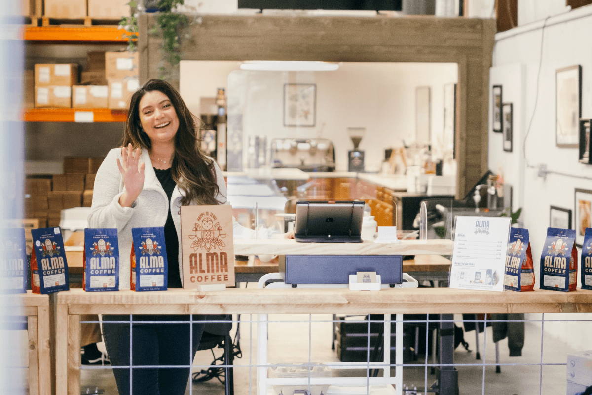 Woman standing and smiling behind a counter.