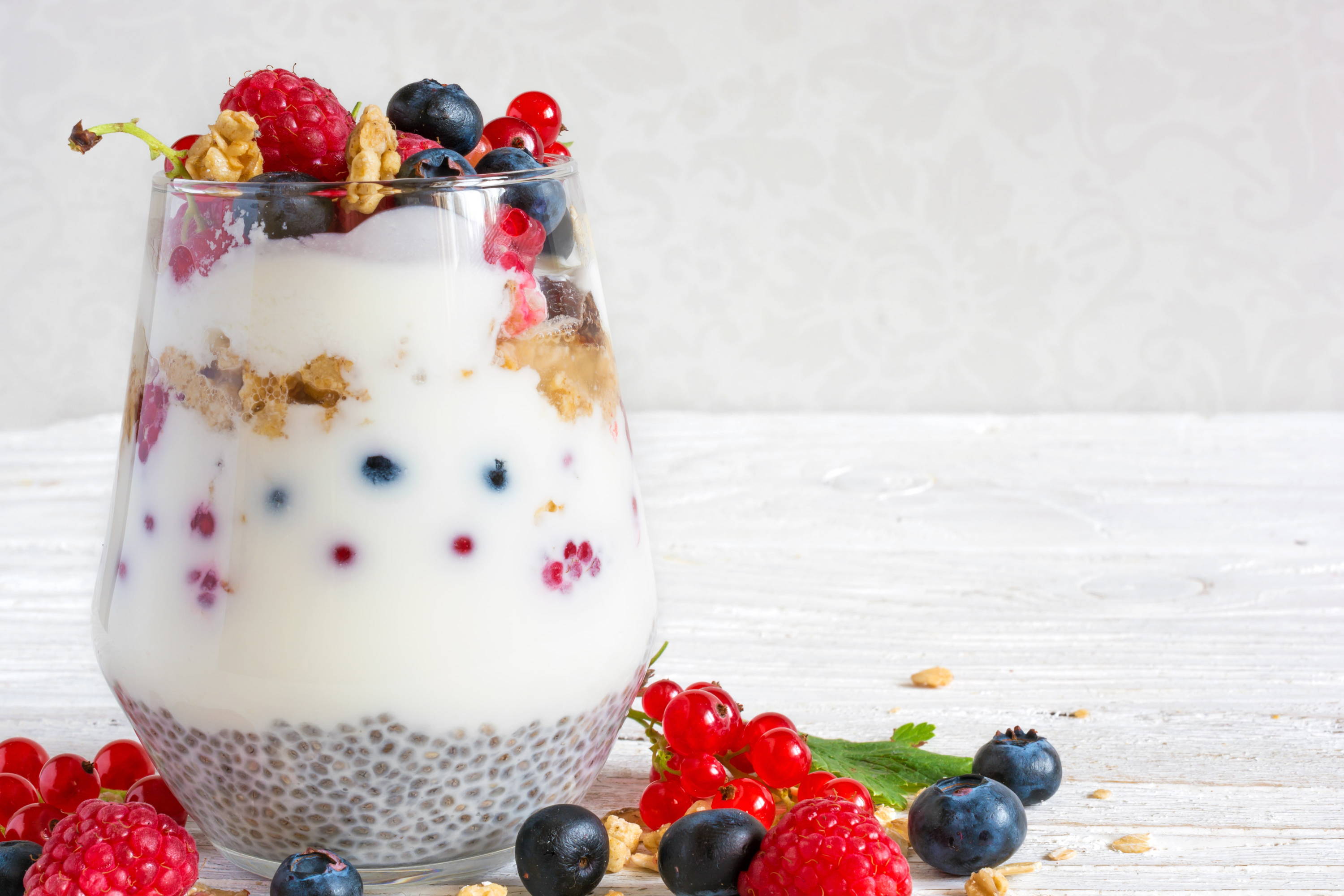 Vegan healthy oats, granola and chia seed pudding with yoghurt and berries in a glass jar. 