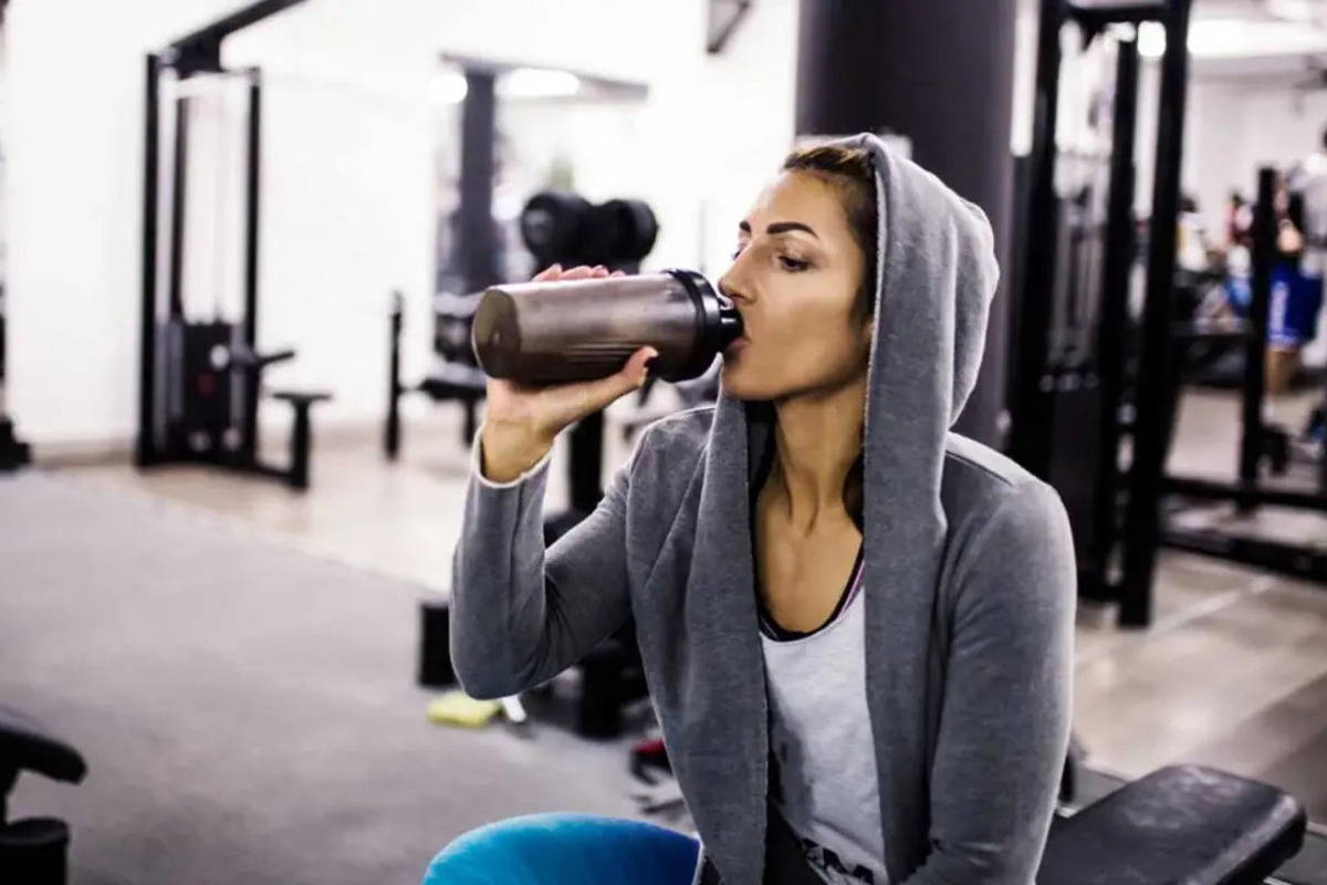 woman in gym drinking protein shake