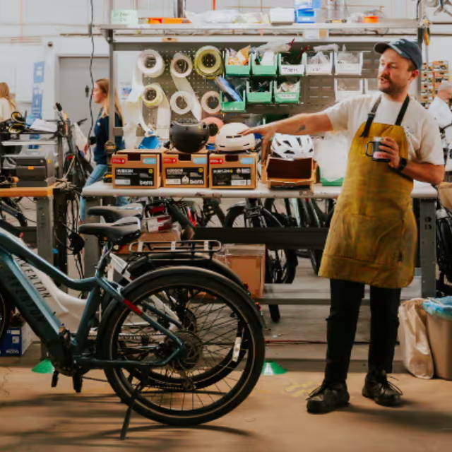 a bike mechanic pointing at electric bikes at an upway upcenter