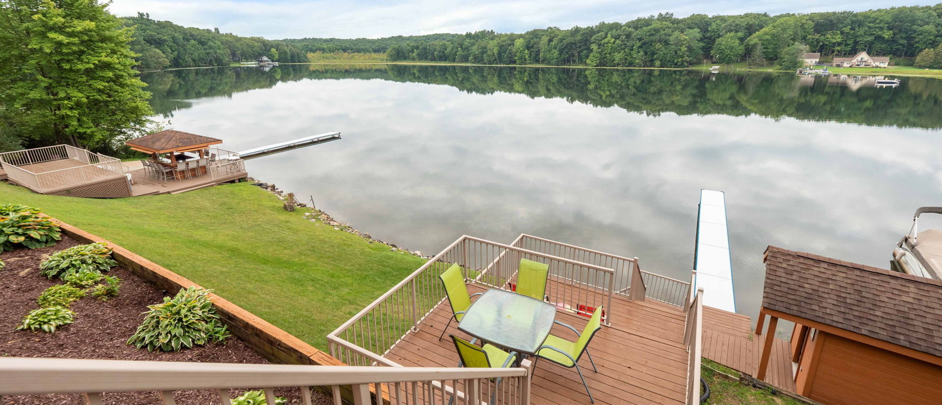 property view of water featuring a deck, a dock, and a lawn