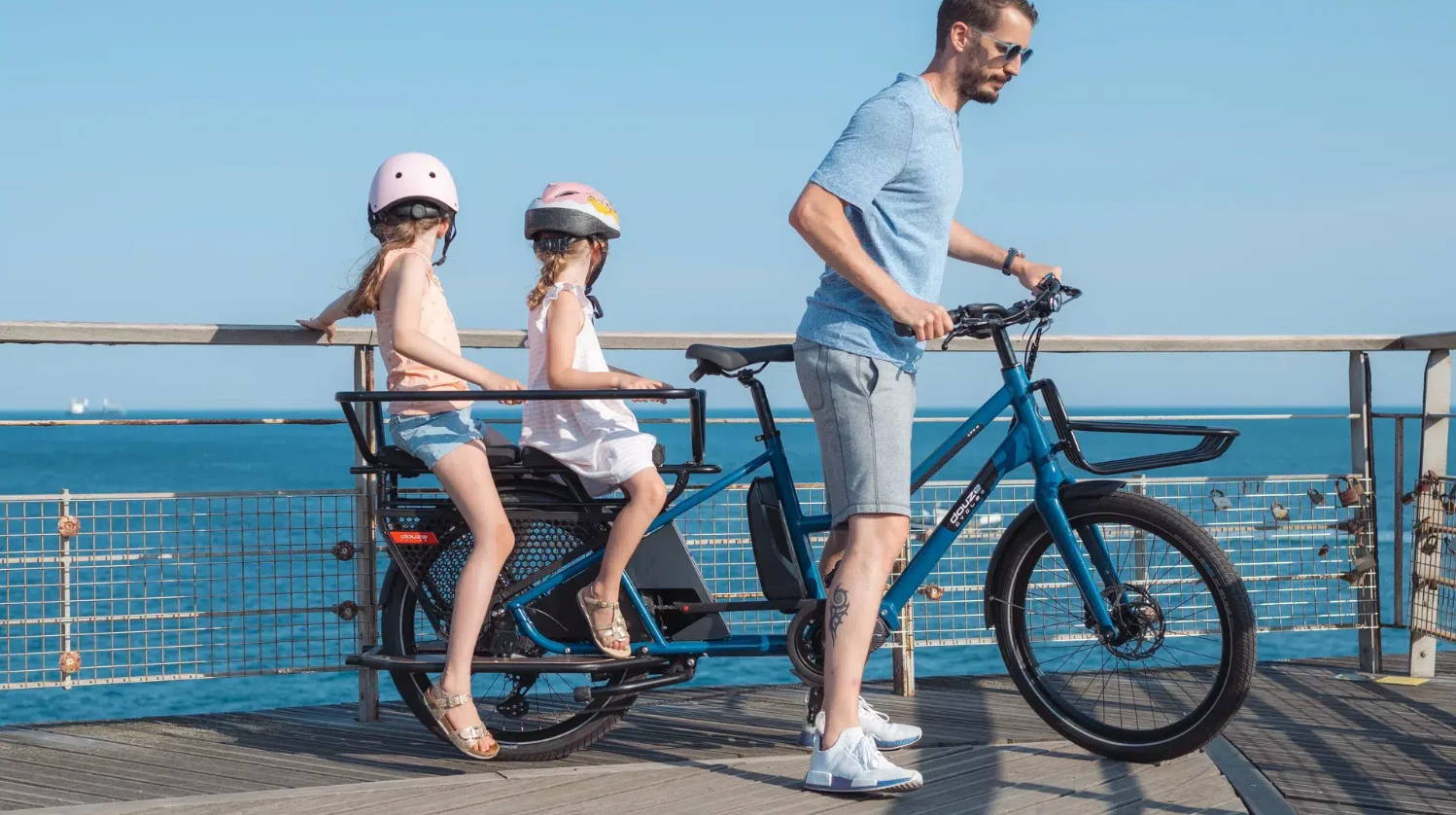 Un papa se balade avec ses enfants sur un vélo cargo longtail ShiftBikes