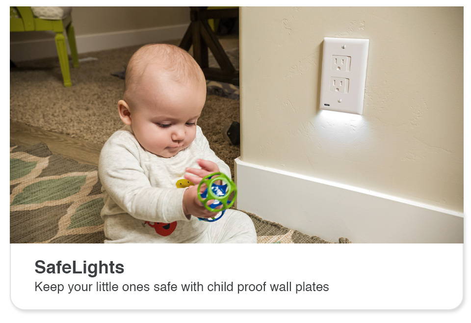 Baby holding toy sitting on the ground next to a SafeLight outlet light cover