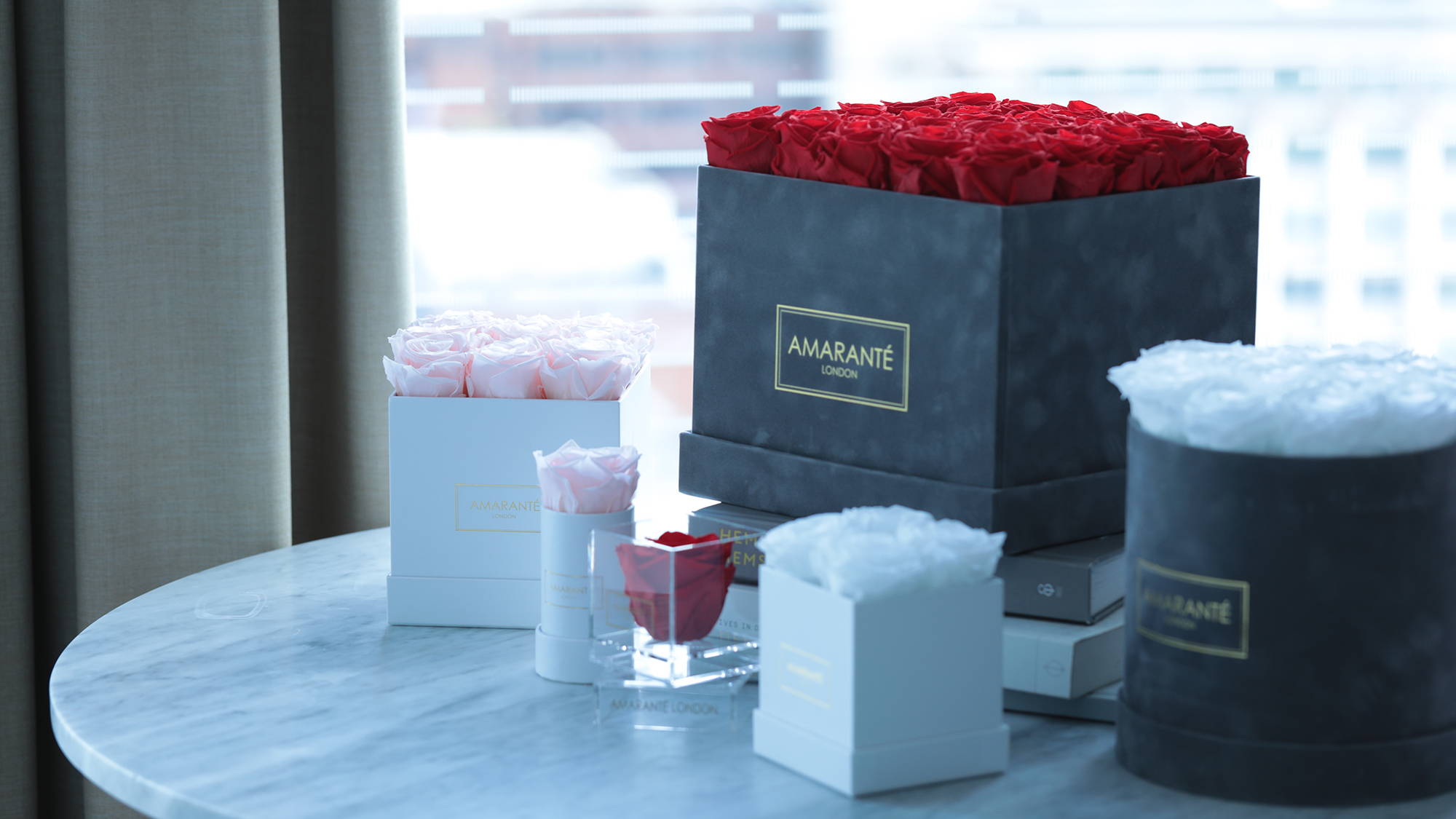 Infinity Roses in hatboxes of different sizes and shapes arranged on a table