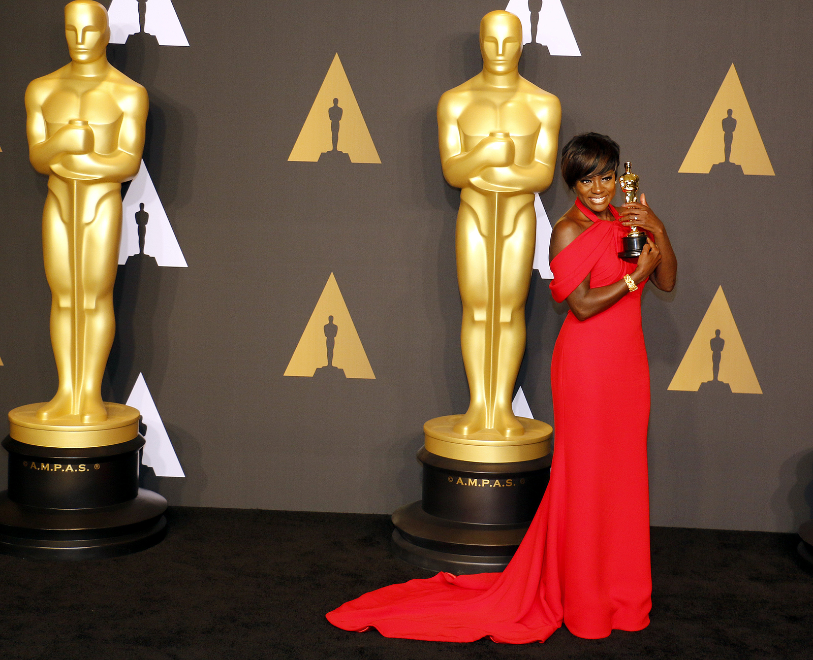 Viola Davis receiving an oscar award with a long red dress.