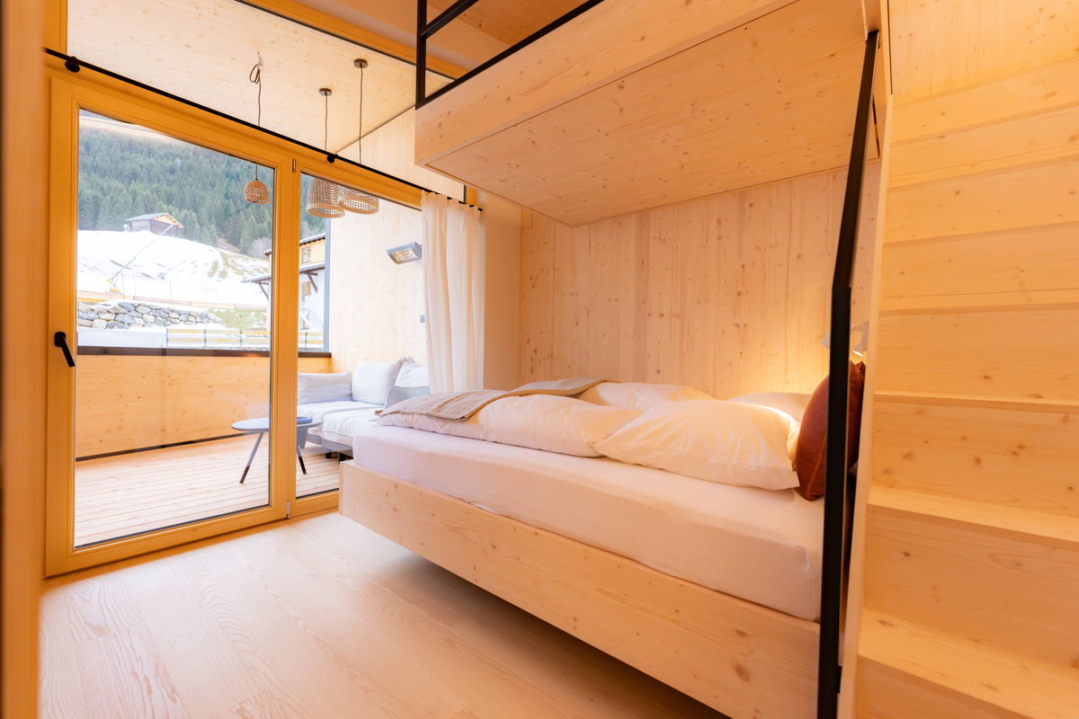 Schlafbereich mit Doppelbett und großer Fensterfront im Zimmer Cozy Kabel in Mittelberg.