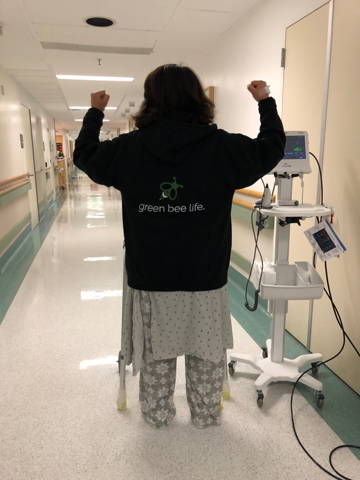 Green Bee Life Founder, Maria Calabrese in the hospital with the assistance of a walker taking her first steps after major spinal surgery.