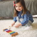 Little girl playing a colorful kids xylophone with wooden sticks.