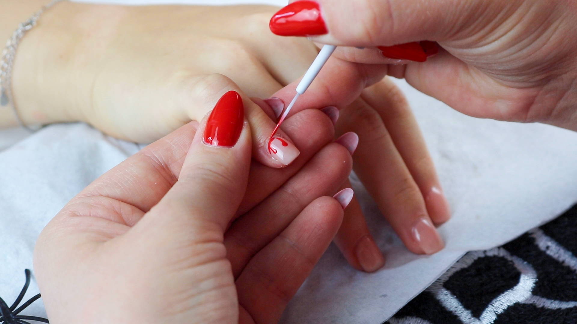 Blood nails detail being added to a nail using a striping brush and ORLY Haute Red