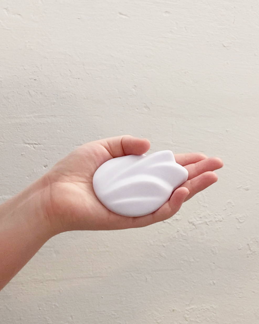 Flex in a hand, showing it's palm sized. The soft squishy silicone is perfect for those who want gentle stimulation.