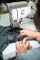 Hands sewing an iaios label on a T-shirt