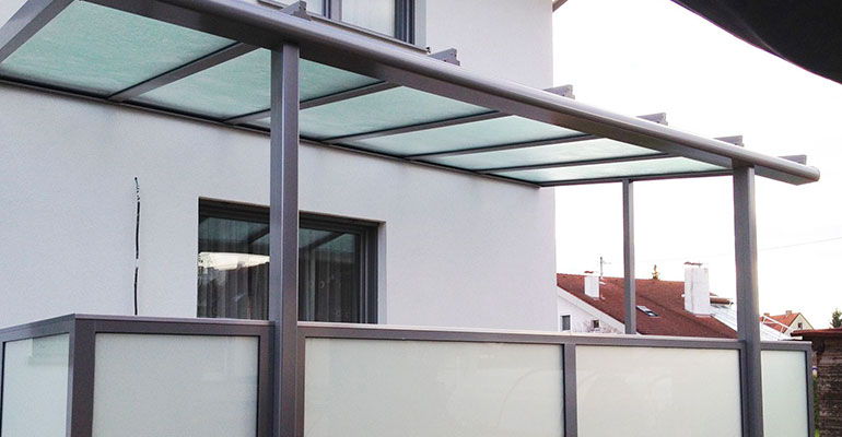 Auvent vitré à structure aluminium au-dessus d’un balcon