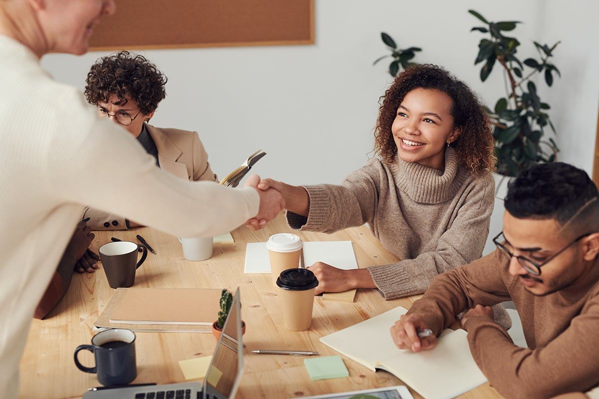 A diverse group of individuals collaborates around a table, engaging with a laptop, focused on ESG partnerships.