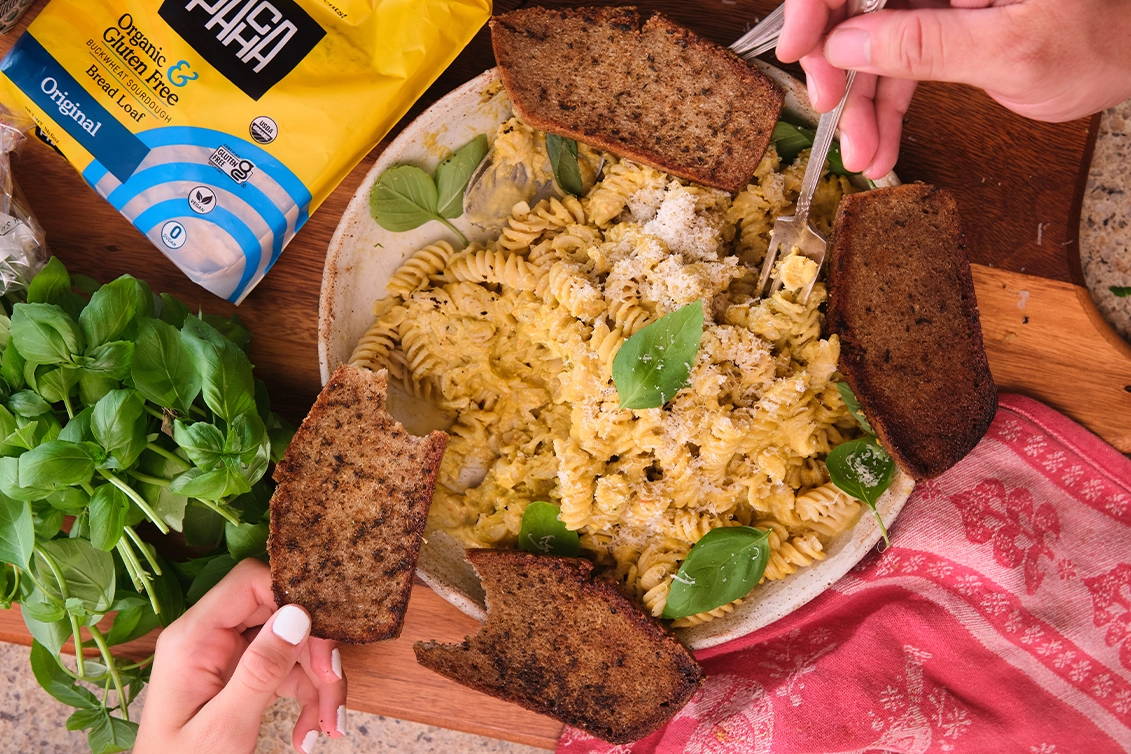 Two small slices of whole grain bread served on a ceramic plate, topped with a spread of seasoned herb butter and olive oil.