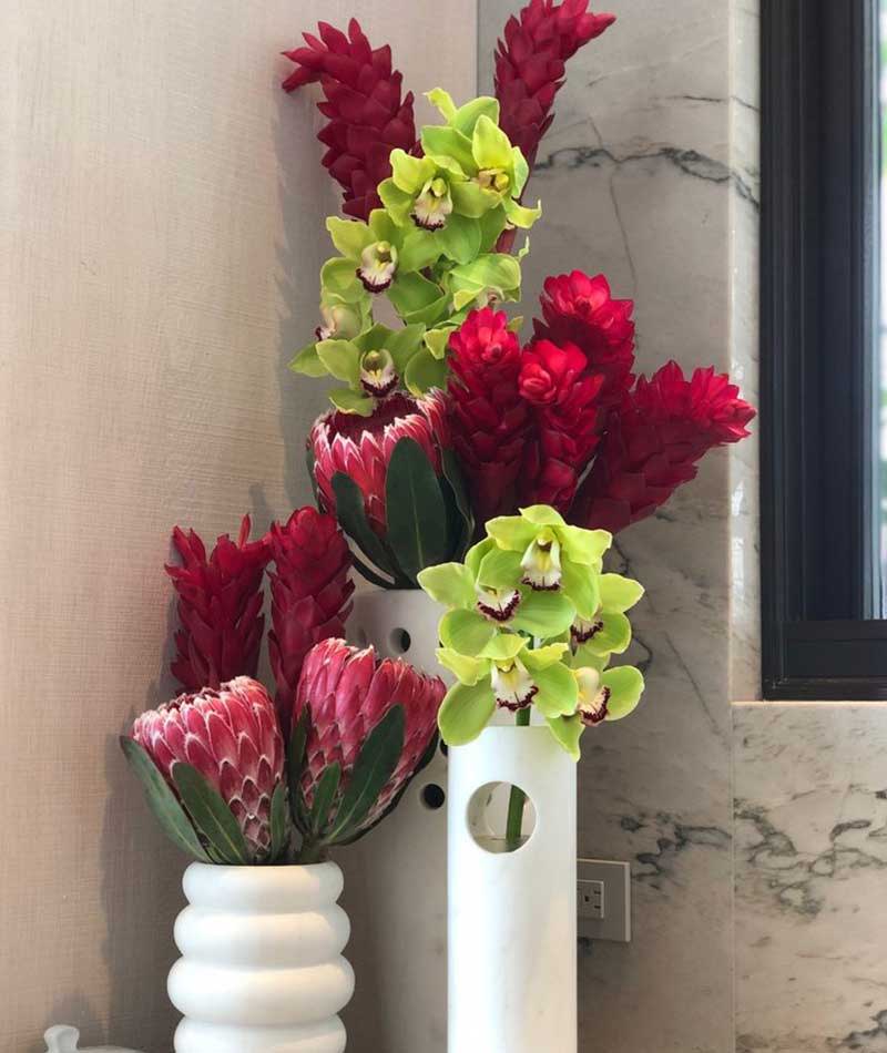 Group of tropical flowers in red and green placed on a corner table