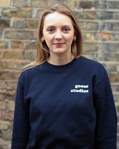 Woman wearing navy blue organic cotton sweatshirt with white printed logo from sustainable clothing brand Goose Studios