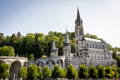 Vue de la cathédrale de Lourdes en été entourée d'arbres