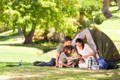 A family of four plays a boardgame while backyard camping