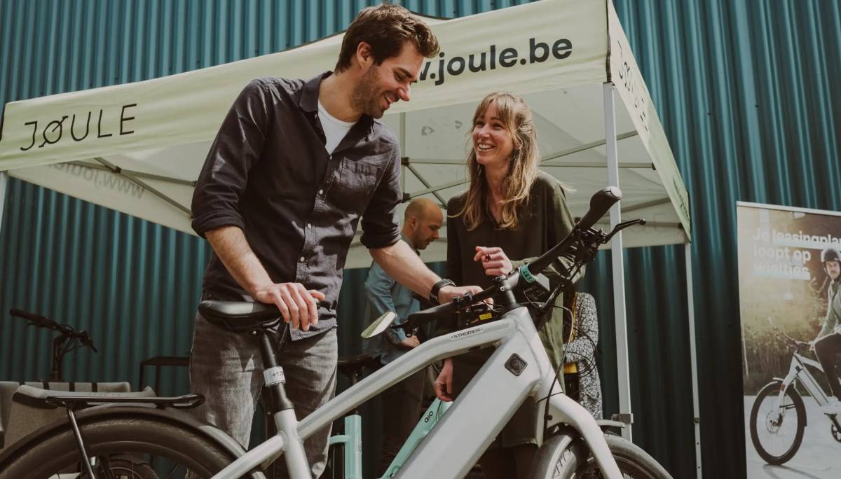 Stand Joule lors d'un événement, un conseiller présente un vélo électrique de leasing à une visiteuse