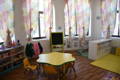 Montessori classroom with round table and toy shelves. 