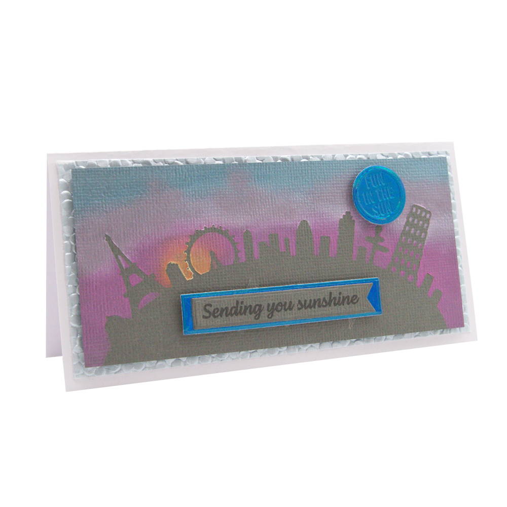 paper crafted card with a sunset over horizon with a city skyline silhouette 