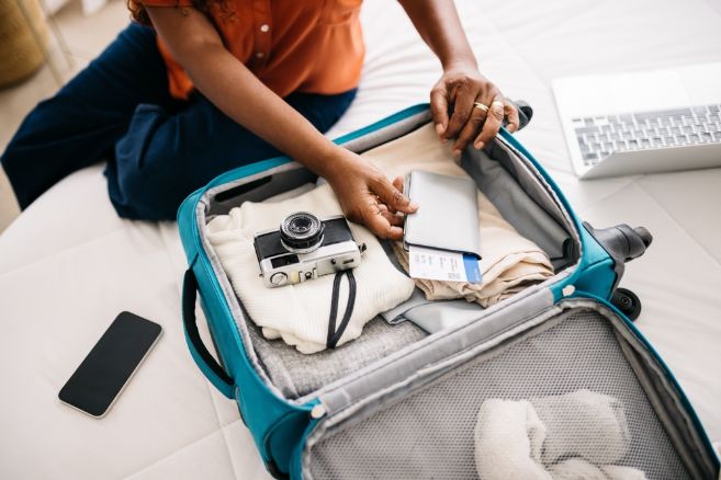 Woman packing the essentials for an exciting global trip, carefully organizing her travel documents and essentials in a suitcase. Retired woman preparing to make unforgettable memories abroad.