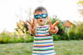 Child wearing sunglasses during summer themed sensory play outdoors.