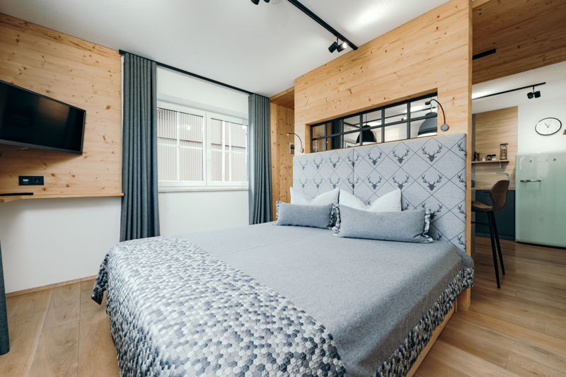 Ein helles, modernes Schlafzimmer mit grau bezogenem Doppelbett.