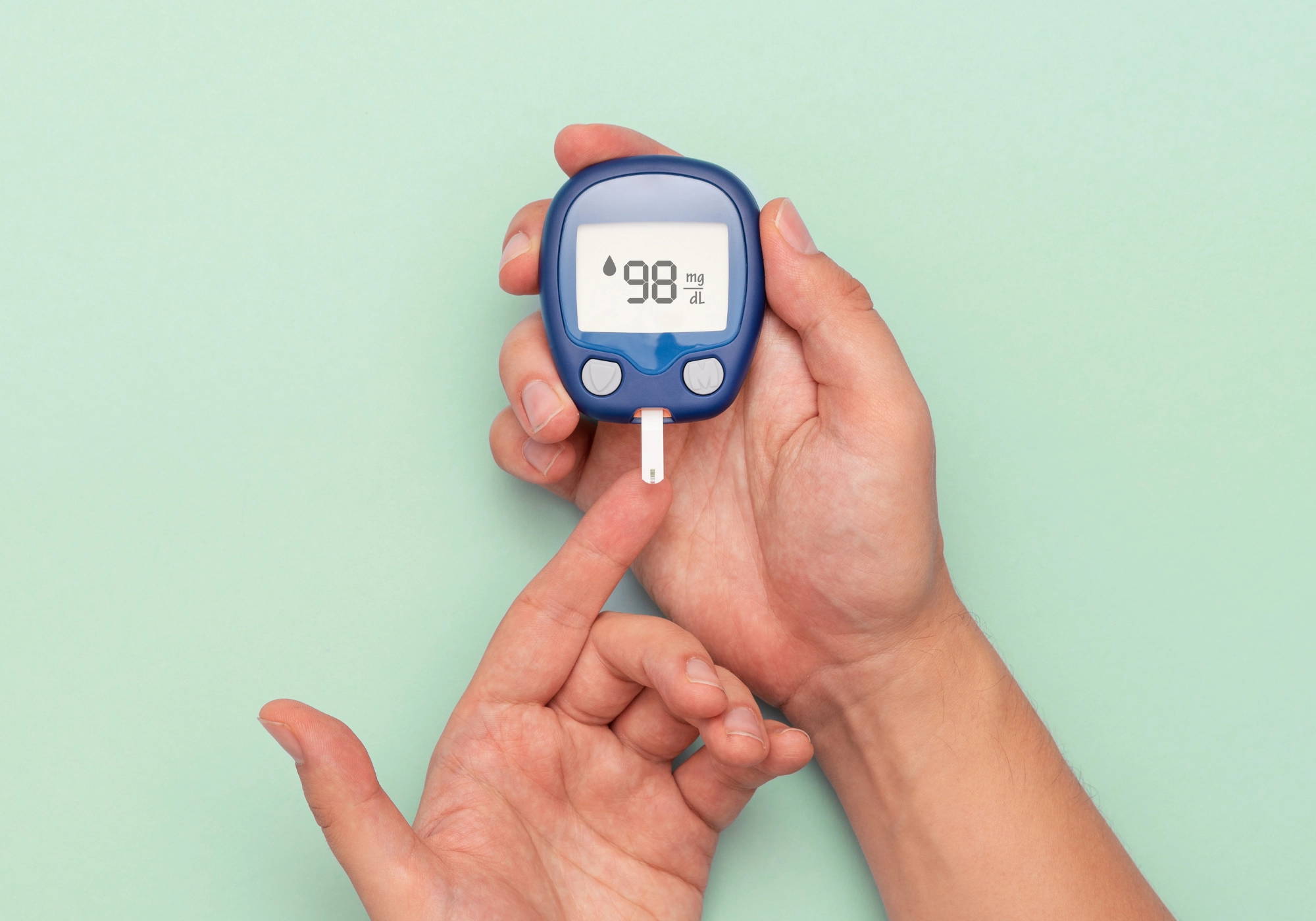 Close-up of hands using a blood glucose meter to check blood sugar levels.