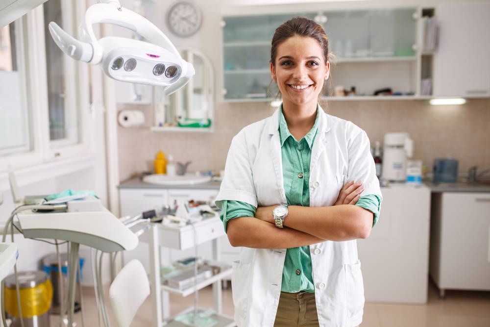Lena-Marie Wagner von Diamond Smile steht lächelnd in ihrer Zahnarztpraxis.