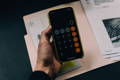 Calculatrice tenue en main devant des papiers de calcul budget