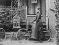 Femme à vélo cadre bas historique devant une maison