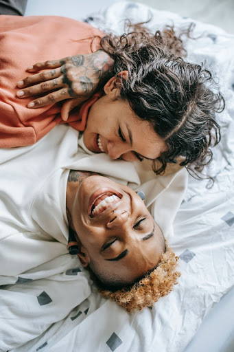 2 people on a bed, hugging and smiling - Photo by Tim Samuel from Pexels