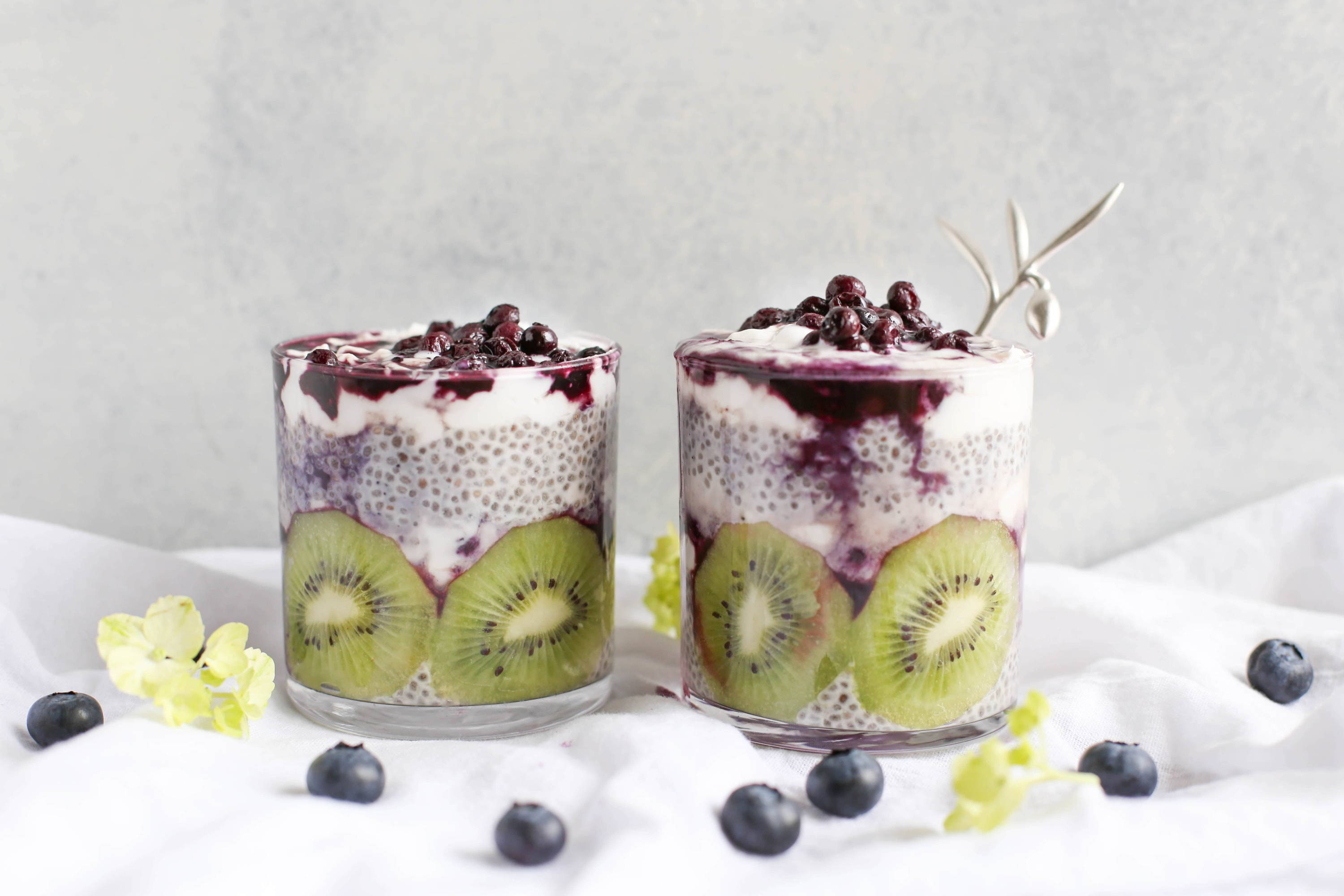 2 glass cups of oats with chia seeds, vegan milk, kiwi and blueberries