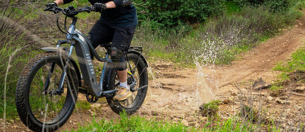 An e-MTB rider on a trail going through a puddle